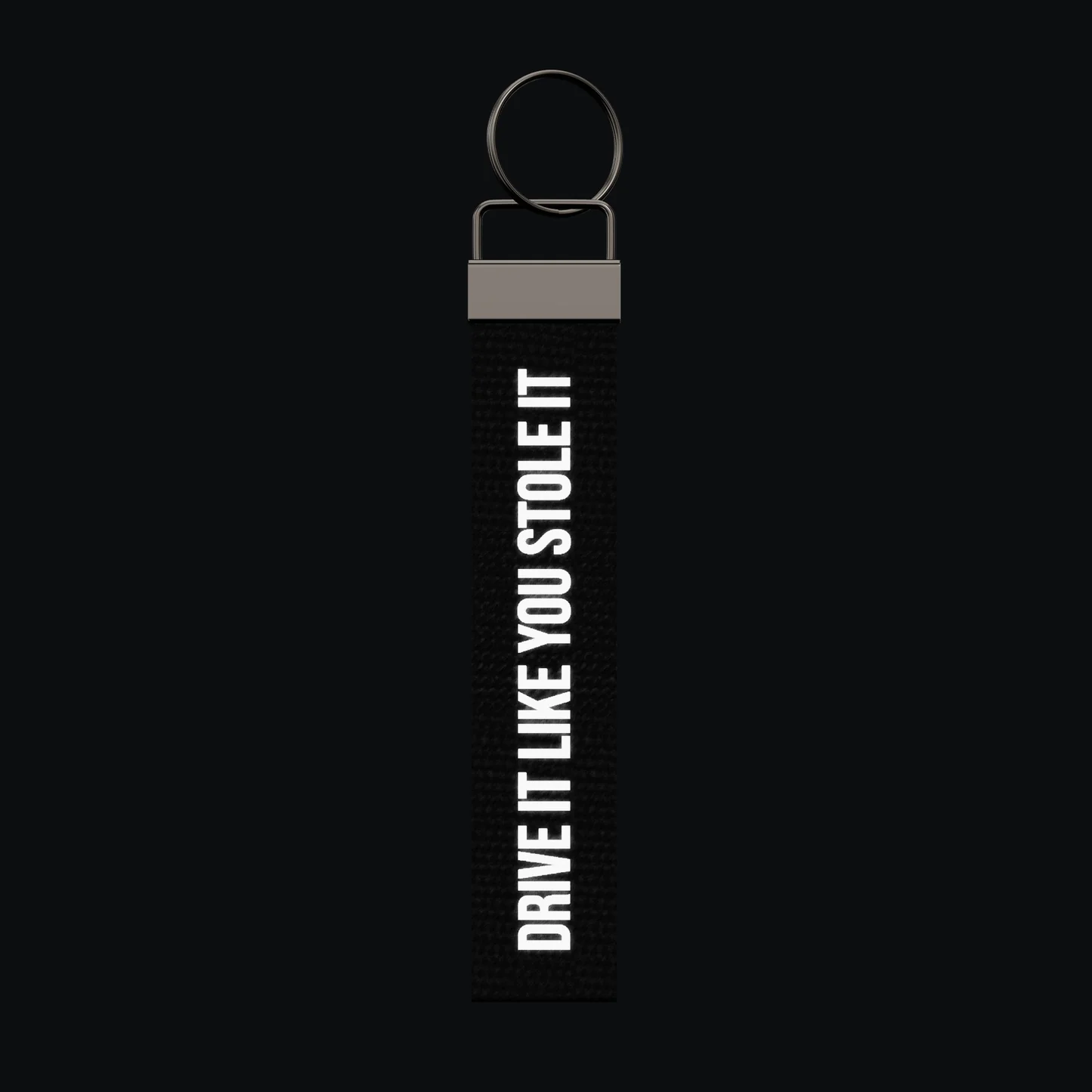 DRIVE IT LIKE YOU STOLE IT Keychain, reflective print lit up by a camera flash