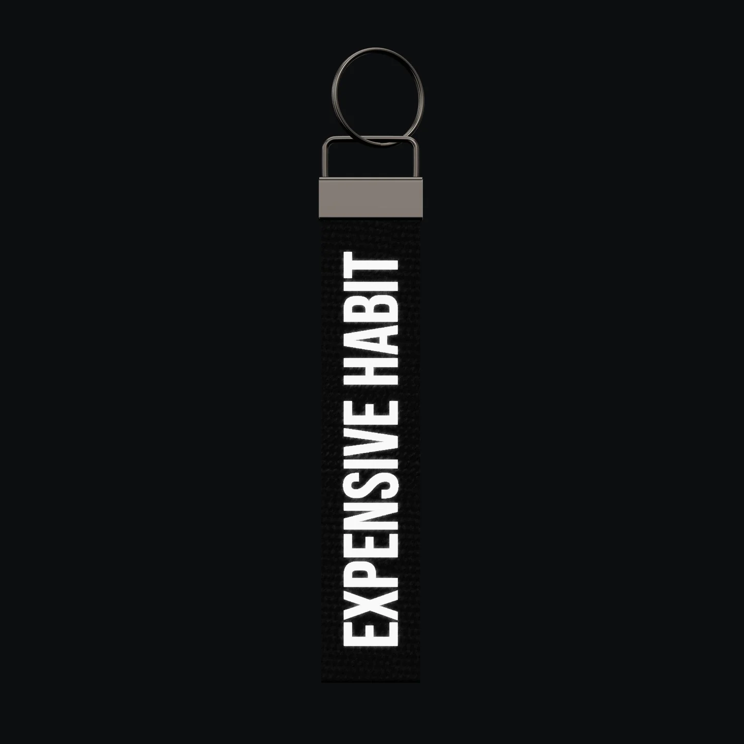 EXPENSIVE HABIT Keychain, reflective print lit up by a camera flash