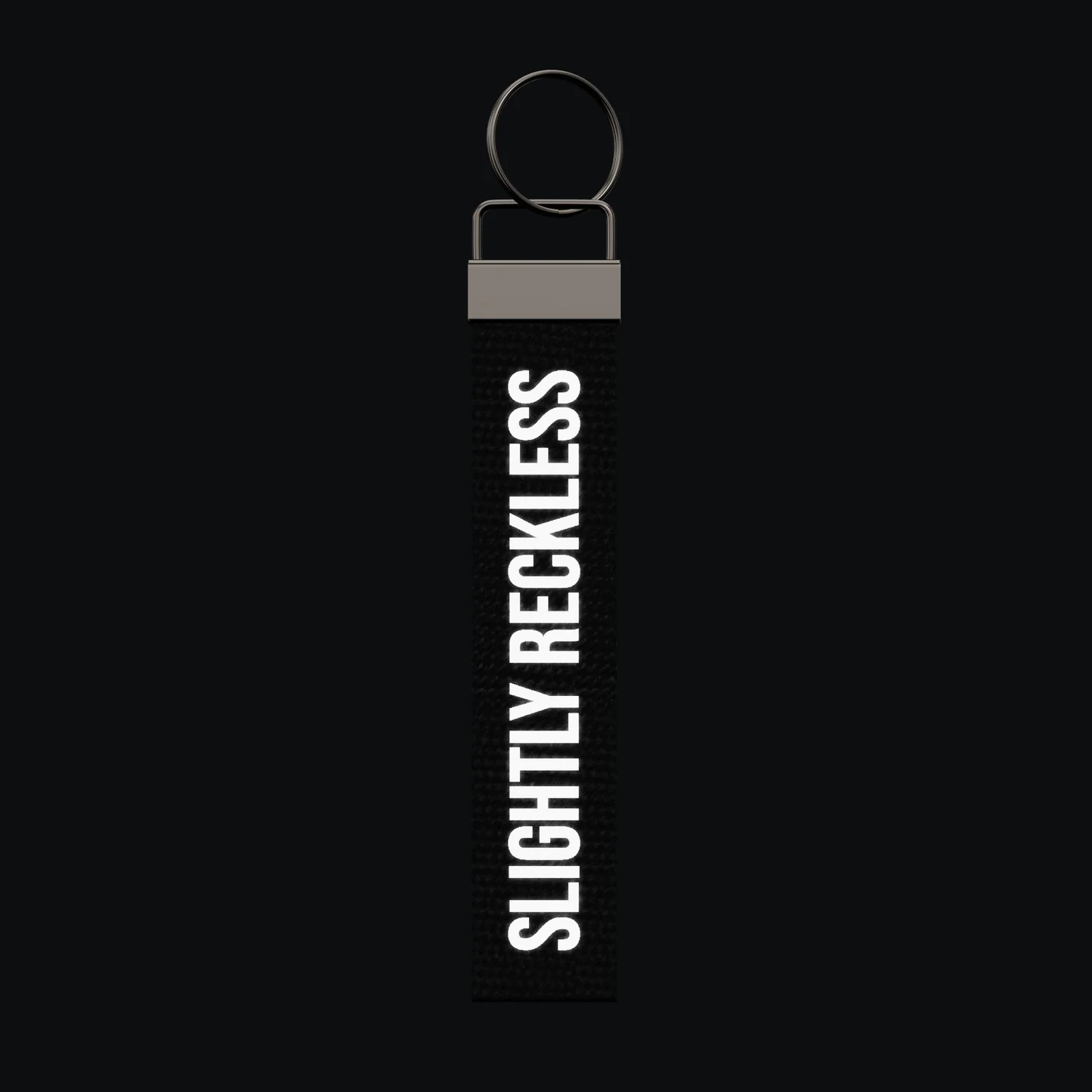 SLIGHTLY RECKLESS Keychain, reflective print lit up by a camera flash