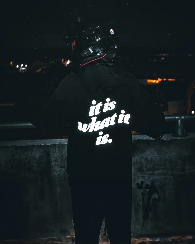 IT IS WHAT IT IS print glowing at night by a concrete wall
